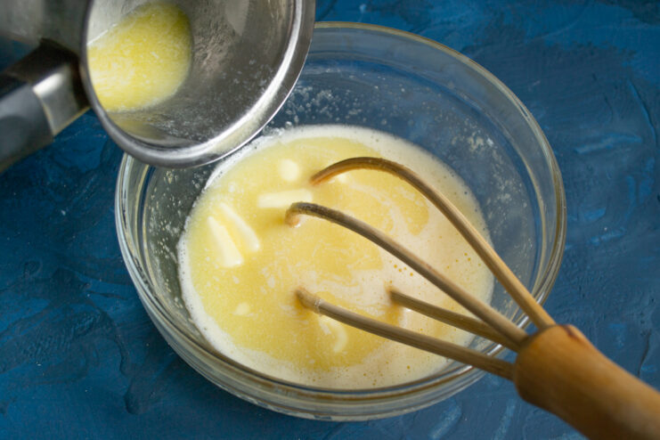 Adding melted butter Pouring melted butter into the bowl of wet ingredients.