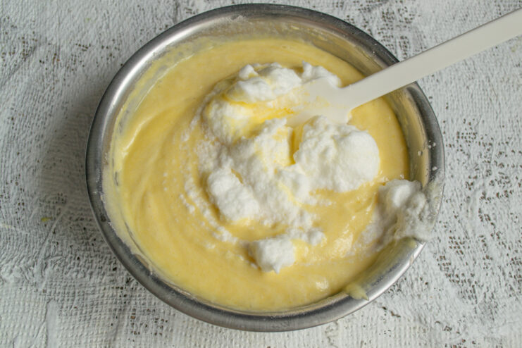 Folding in Egg Whites Folding whipped egg whites into the yellow cake batter with a spatula.