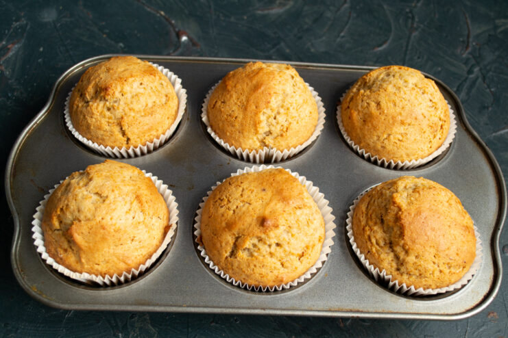 Checking For Doneness Freshly baked golden brown muffins sitting in a metal tin