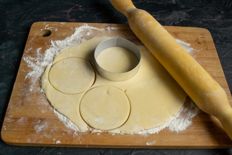 Cutting round shapes out of rolled shortbread dough using a cookie cutter.