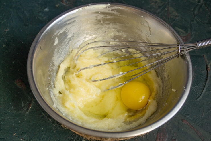Whisking the egg into the batter Fluffy butter mixture being whisked with a fresh egg.