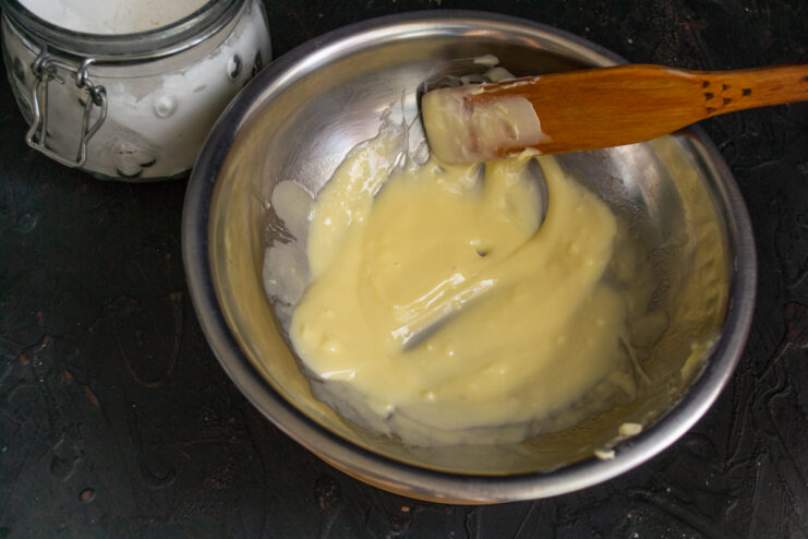 Whipping the Buttercream Whipping buttercream in a bowl with a wooden spatula