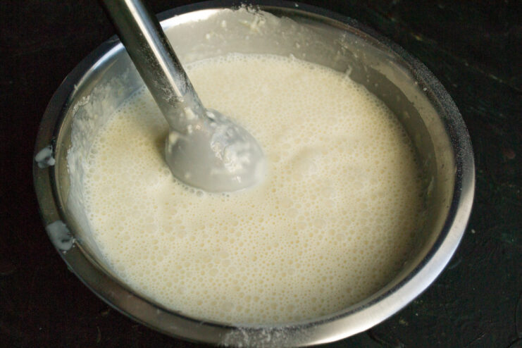 Blending the batter with an immersion blender in a metal bowl.