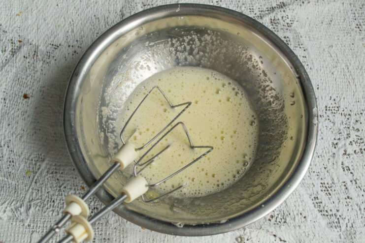 Whisking eggs for the batter Whisking eggs and sugar in a metal bowl to make the cake batter