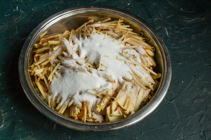 Adding spices to apples Apples sprinkled with sugar and cinnamon in a pot before cooking