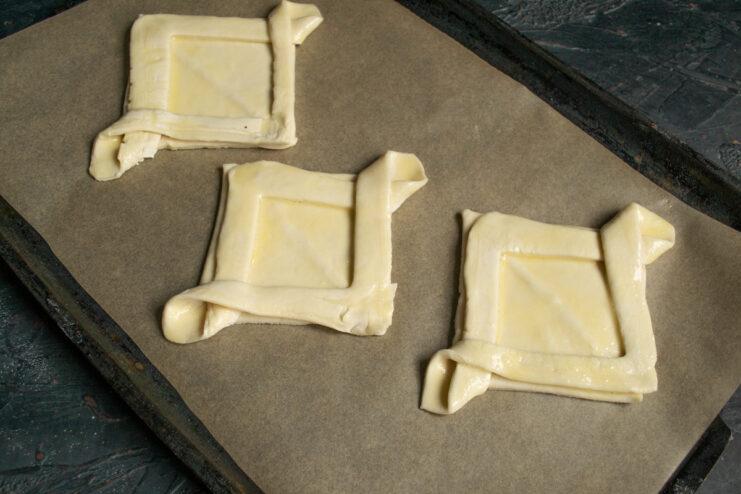 Raw puff pastry shapes arranged on a parchment-lined baking sheet
