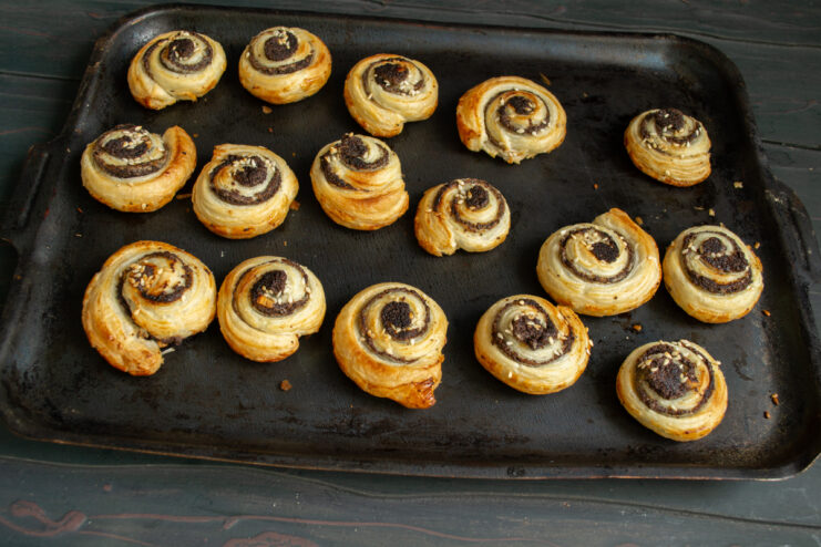Baked golden pastries Golden brown baked poppy seed pinwheels on a baking sheet.