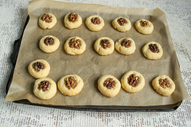 Baking the cookies Baked golden shortbread cookies with walnuts on a baking sheet