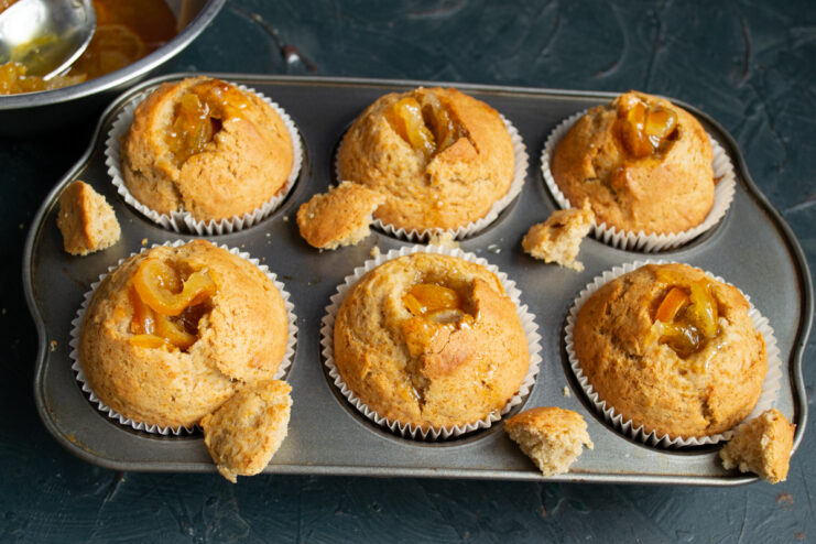 Filling With Marmalade Spoon filling the hollowed muffin centers with orange marmalade