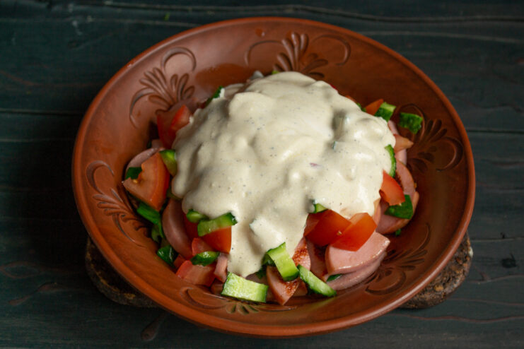 Dressing The Salad Drizzling the vegetable layers with sour cream dressing