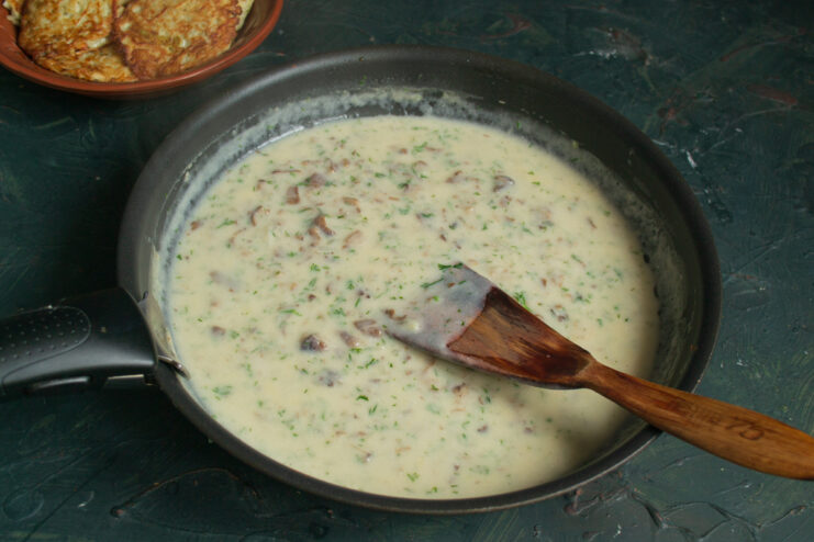 Finishing the sauce Fresh dill stirred into a rich mushroom sauce in a pan