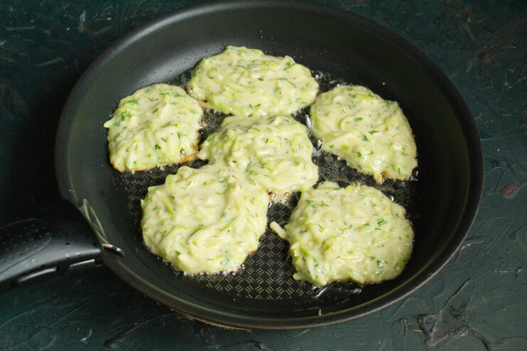 Frying The Fritters Frying round zucchini fritters in a hot skillet