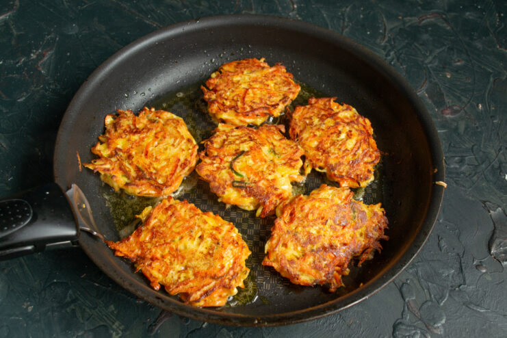Crispy golden brown carrot fritters frying in a pan
