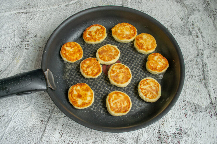 Frying Until Done Flipping golden brown syrniki in a hot frying pan
