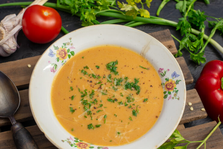 Appetizing creamy salmon soup in a bowl garnished with fresh herbs and Parmesan cheese