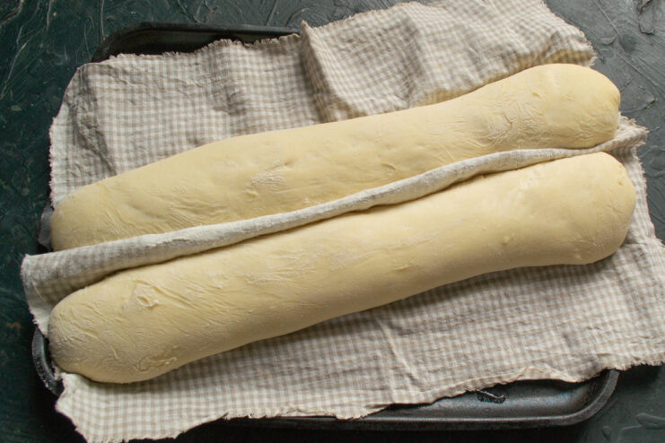 Proofed baguette dough resting on a baking sheet
