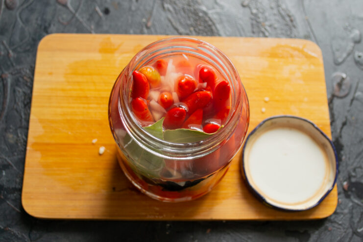 Pouring the marinade Glass jar filled with chili peppers covered in hot spiced marinade