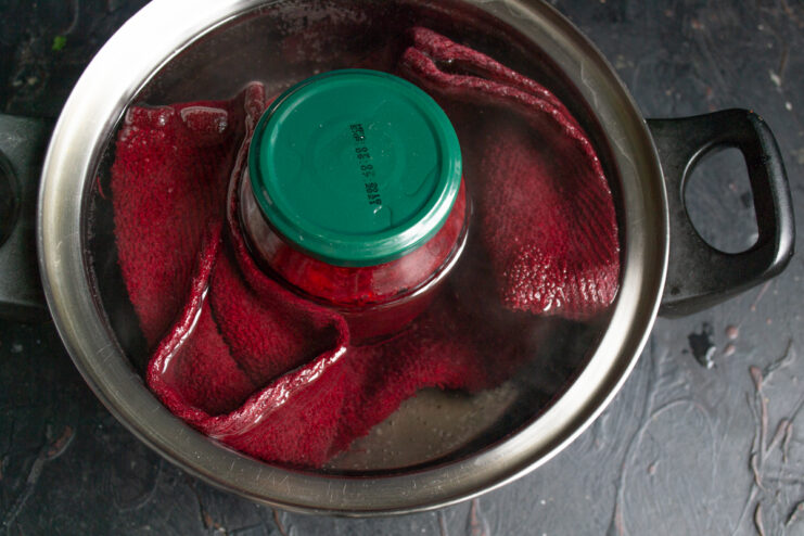 Sterilizing jars with the preserve Jar of borsch base sterilizing in a pot of boiling water.
