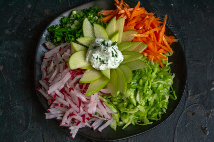 White dressing placed in the middle of an apple flower on a vegetable assortment