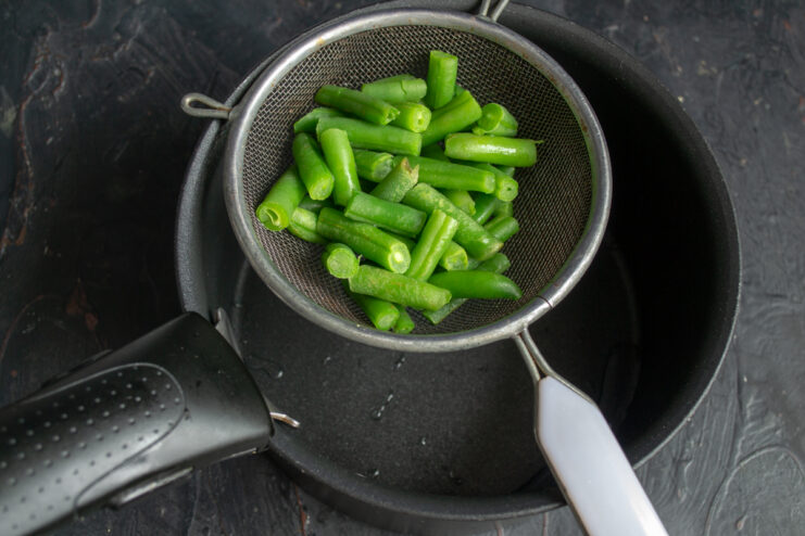 Preparing The Green Beans Blanched green beans draining in a metal sieve