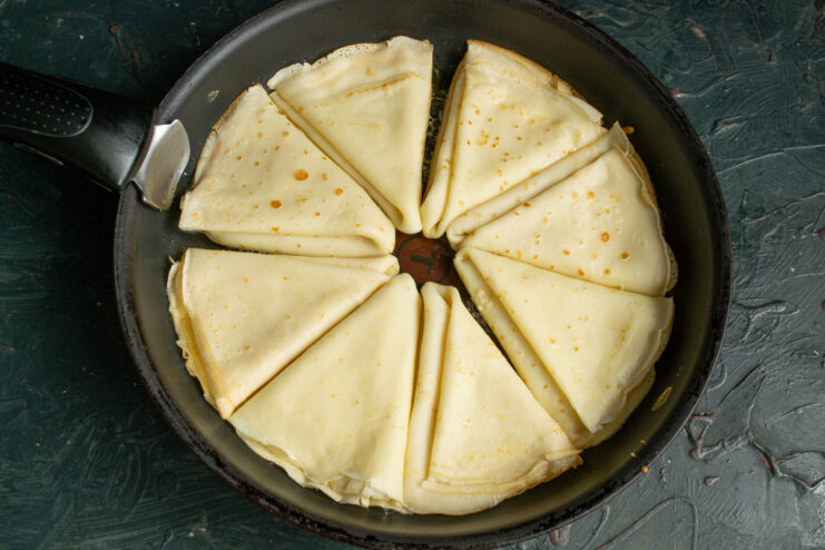 Folded crepes frying in a skillet with melted butter