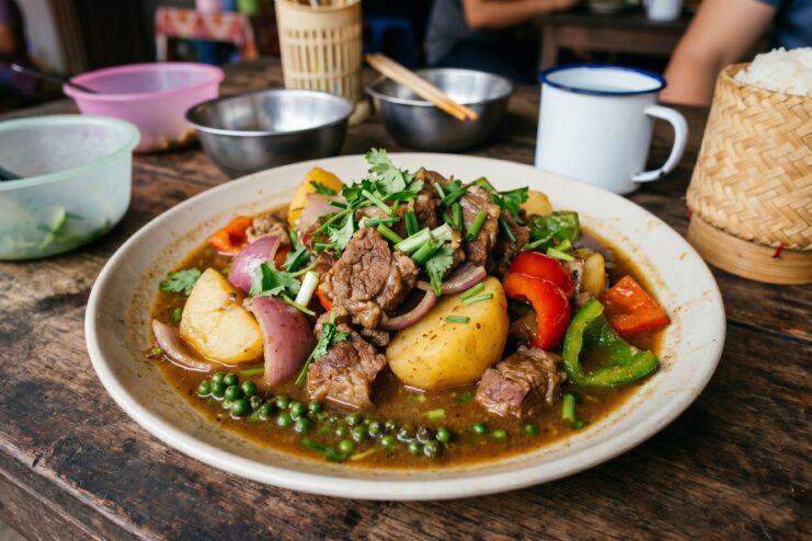 An Asian-style dish featuring braised meat, potatoes, and whole green peppercorns.