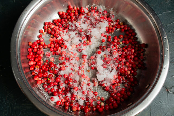 Fresh lingonberries and sugar cooking in a saucepan