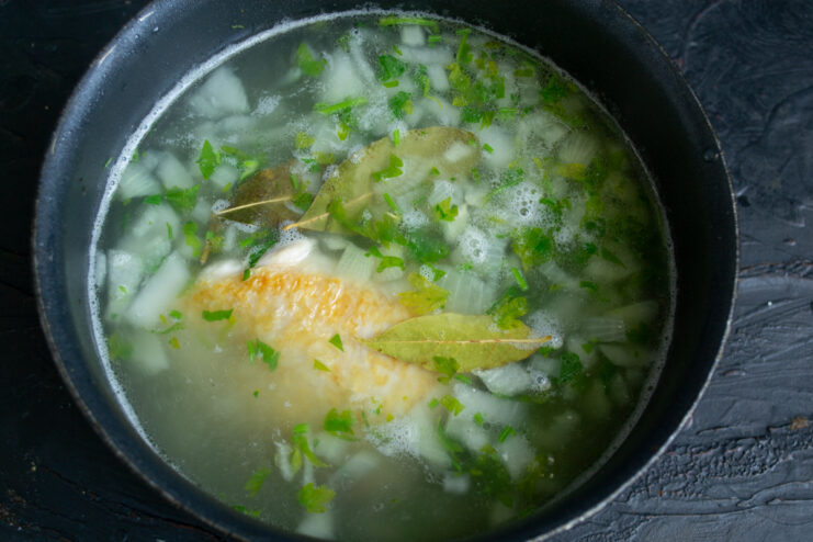 Simmering The Broth Chicken broth cooking with onion and a bay leaf