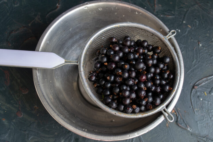 Preparing The Berries Fresh blackcurrants in a metal mesh strainer