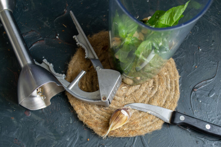 Adding garlic Pressing a fresh garlic clove into the blender bowl with herbs