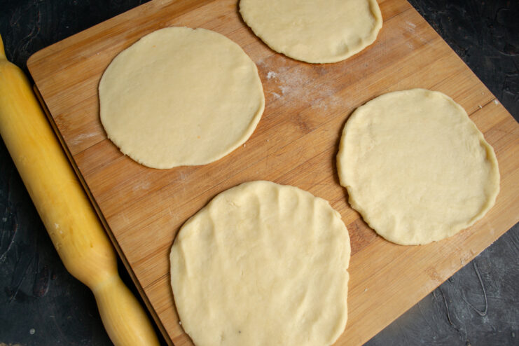 Rolling out the dough circles Four round dough circles rolled out on a lightly floured board