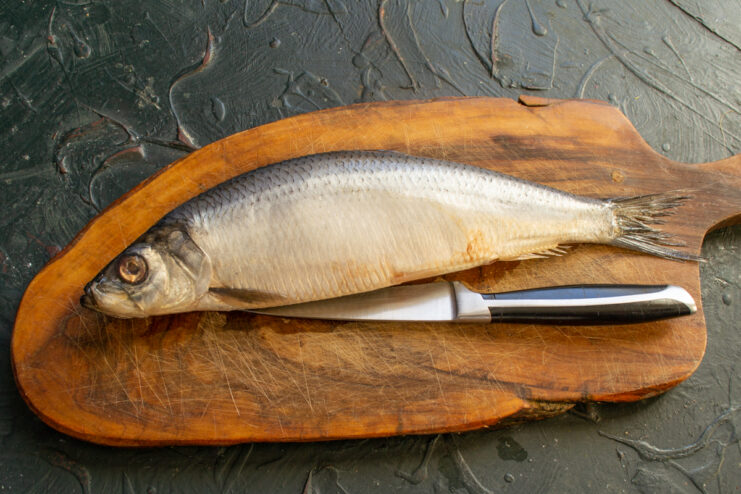 Preparing whole herring Whole salted herring on a cutting board with a knife