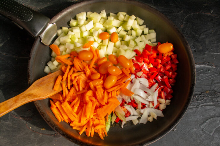 Whole cherry tomatoes added to the skillet with diced vegetables.