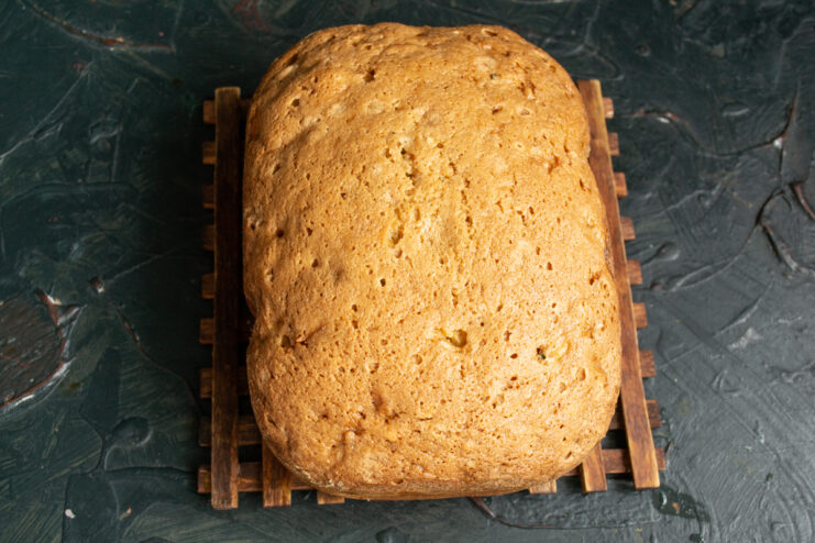 Whole baked carrot loaf cake resting on a wooden board