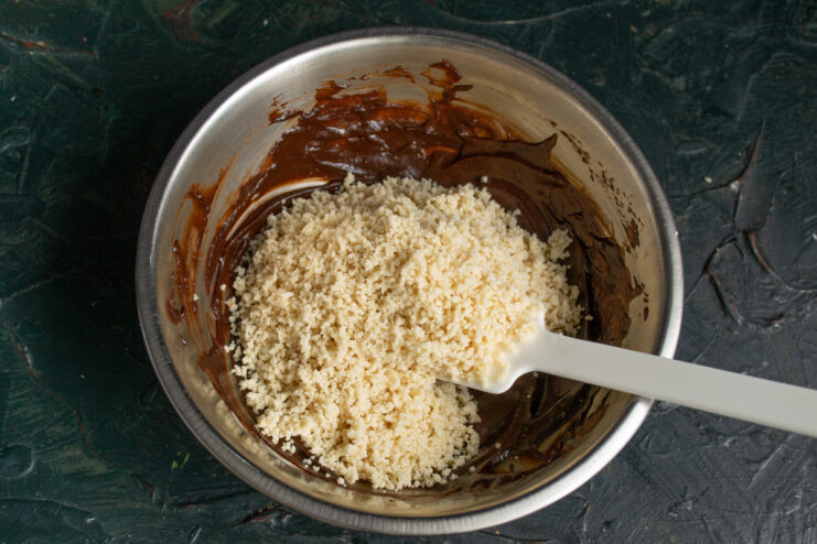 Mixing chocolate and peanuts Pouring ground peanuts into a bowl of melted chocolate