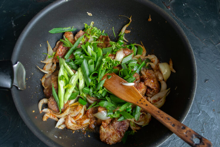 Adding Fresh Greens Tossing chopped cilantro and green onions into the wok with chicken livers