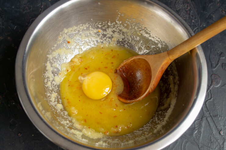 Adding the egg Cracking a raw egg into a butter and sugar mixture