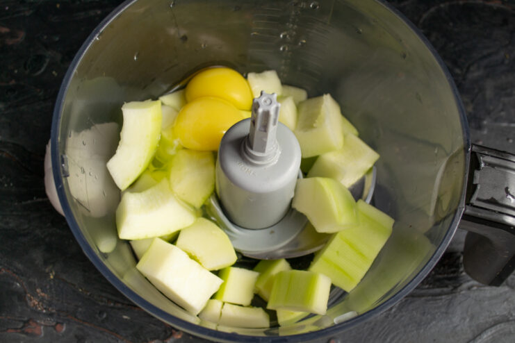 Adding whole eggs to the diced zucchini in a blender
