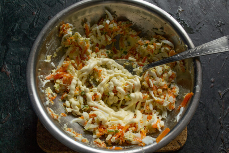 Adding mayonnaise into the bowl of herring roll filling.