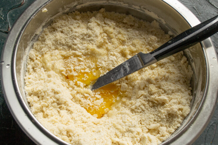 Kneading the Pastry Dough Adding diced butter and a beaten egg to dry tart dough ingredients