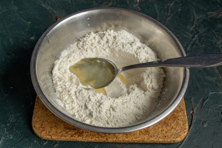 Pouring vegetable oil into a bowl of flour