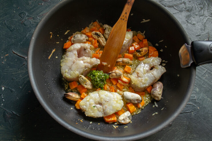 Adding seafood and spices Adding shelled mussels and spicy garlic paste to the pan