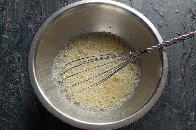 Pouring milk into the whisked egg mixture in a bowl