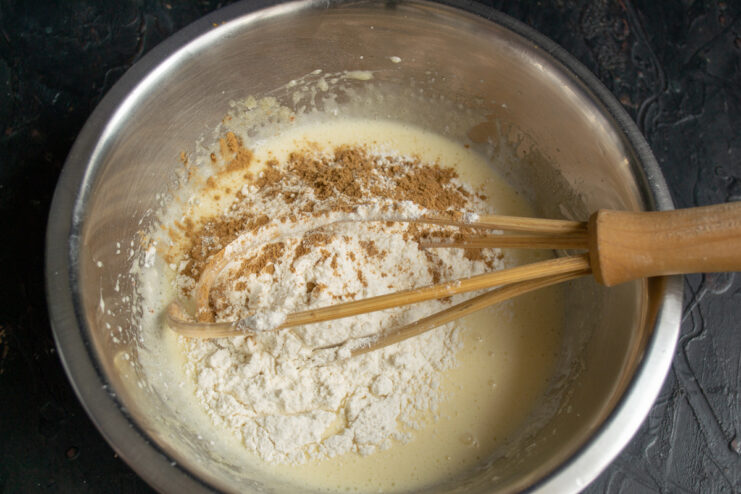 Mixing wet and dry ingredients Adding flour and cinnamon to wet ingredients in a bowl
