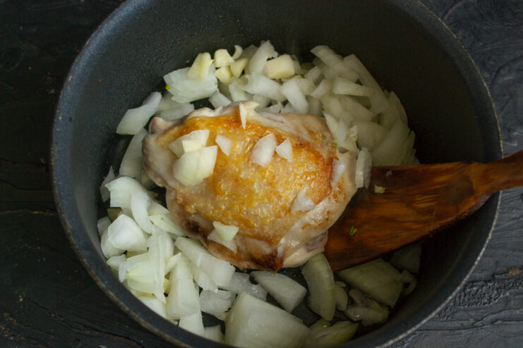 Sauteing Onion And Garlic Adding chopped onion to the seared chicken in a pot