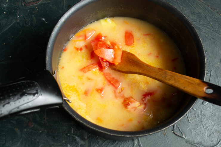 Adding tomatoes Adding chopped ripe tomatoes to the simmering vegetable soup