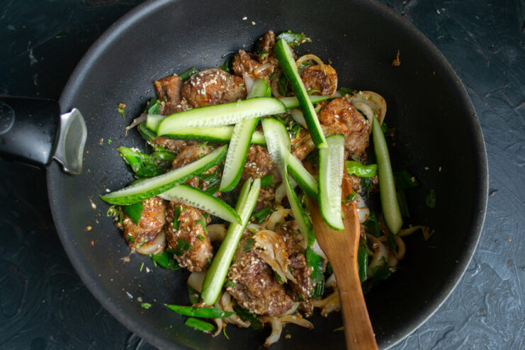 Finishing with Cucumbers and Sesame Stirring fresh cucumber strips and sesame seeds into the warm liver salad