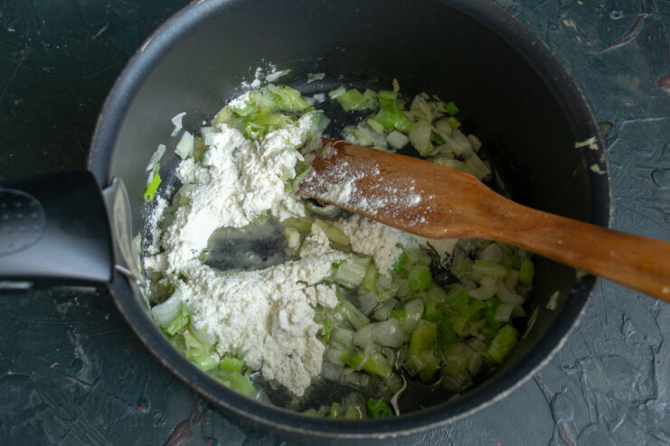 Adding flour to the soup base to thicken it into a creamy texture