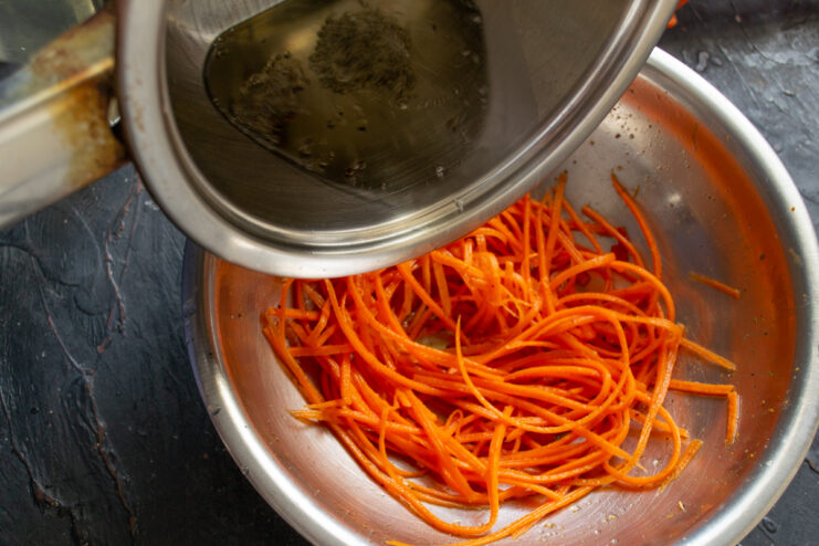 Adding Hot Oil Pouring sizzling hot oil with spices over julienned carrots