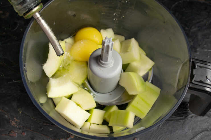 Pouring vegetable oil into a blender with zucchini and eggs